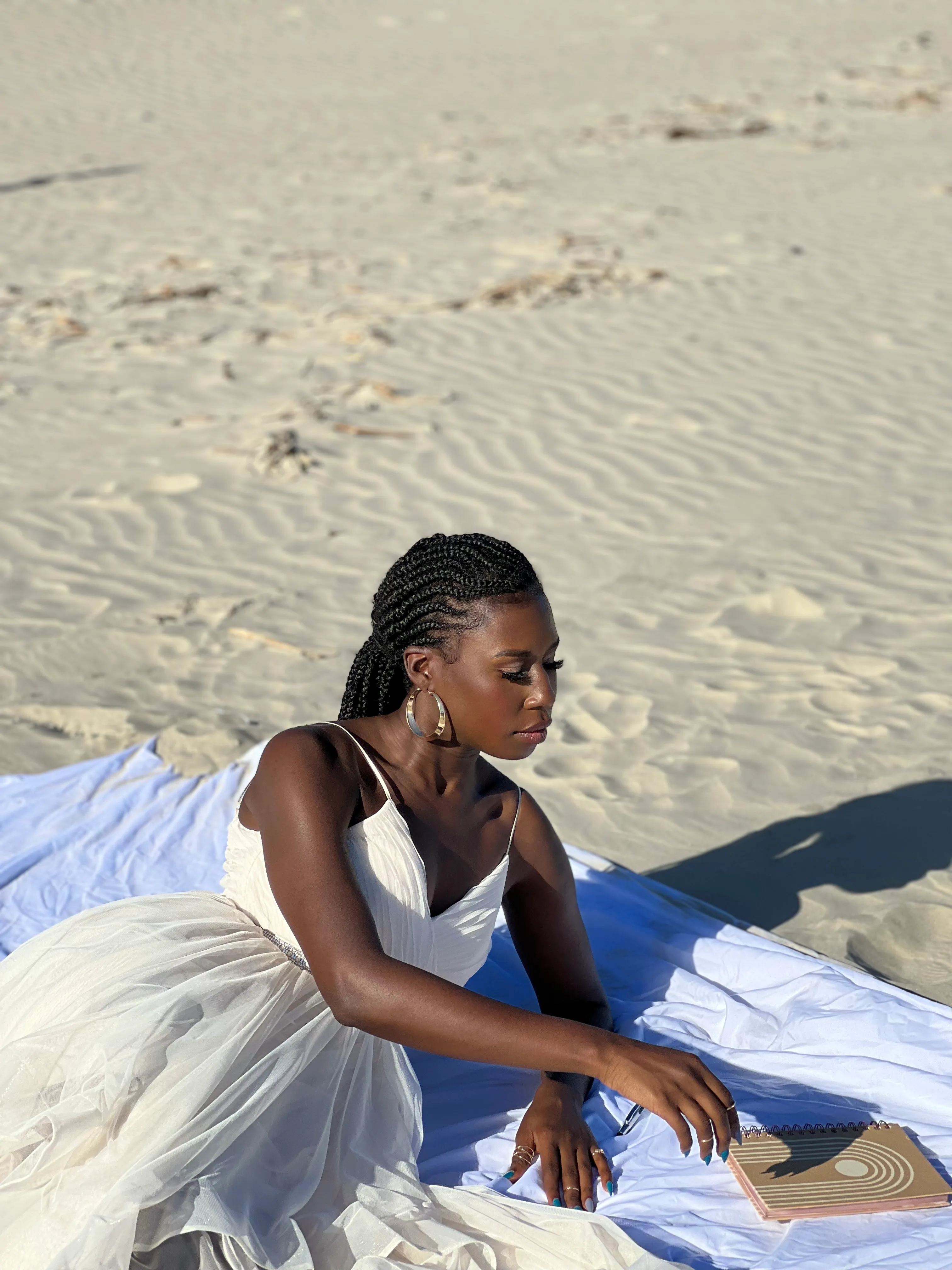 Nala sitting on the beach writing in a notebook