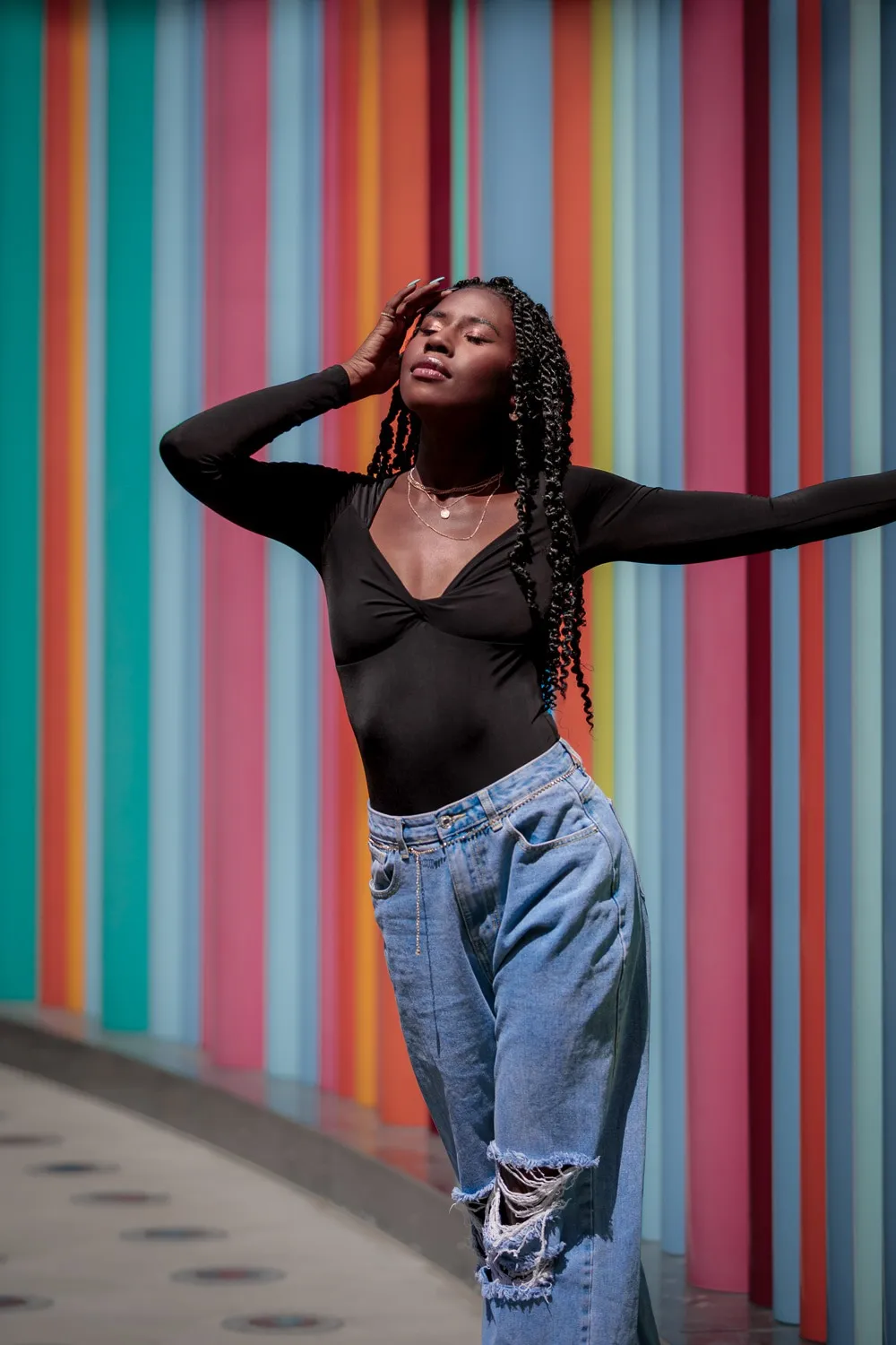 Nala against a colorful striped wall, arm raised