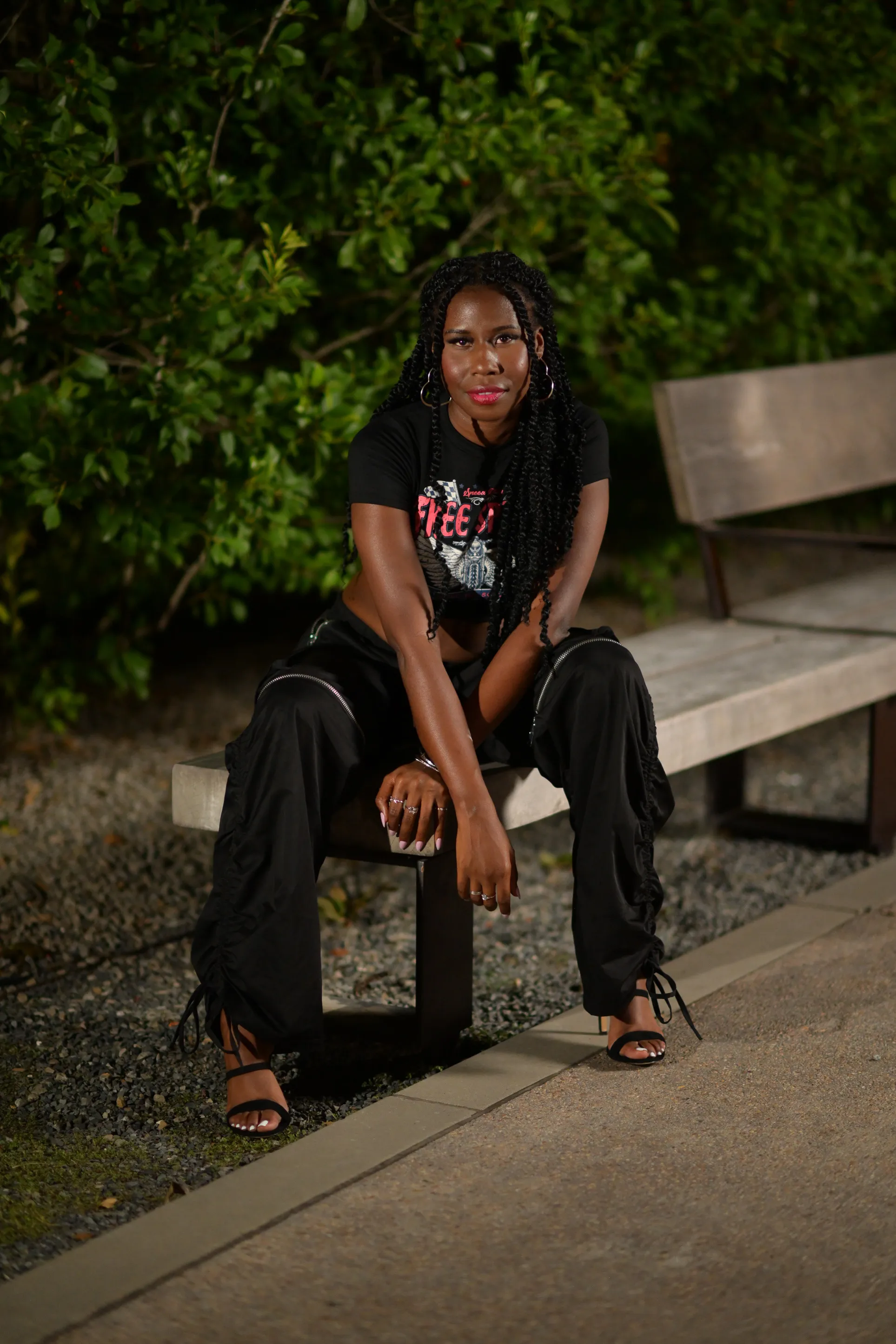 Nala seated on a bench at night in a black outfit
