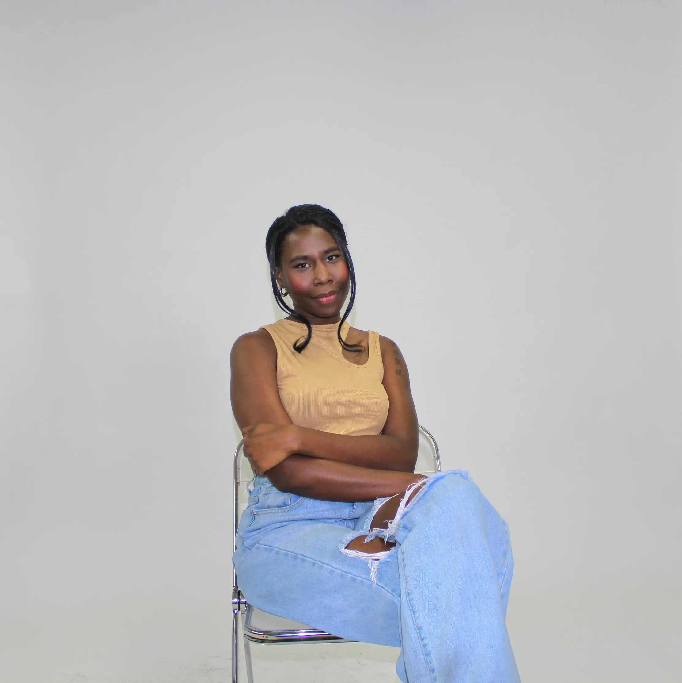 Nala seated in a tan tank top against a grey studio backdrop