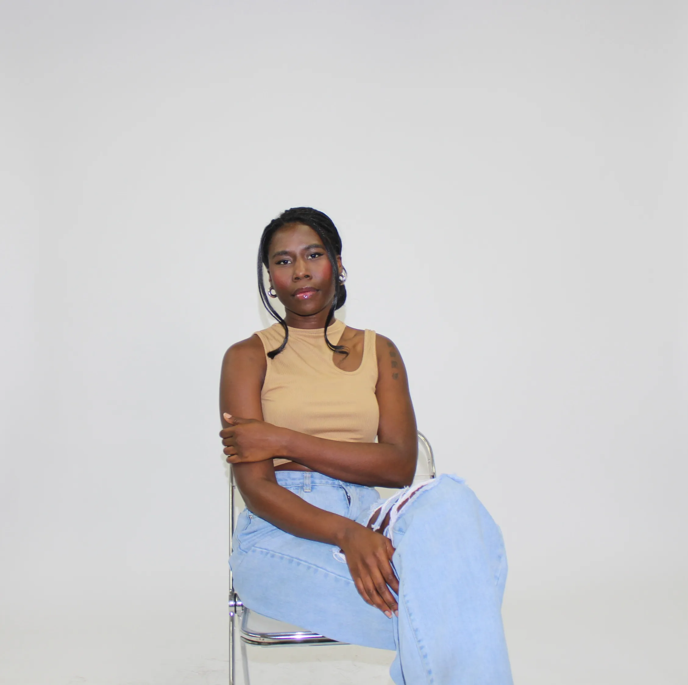 Nala in a tan tank top, arms crossed, grey studio backdrop