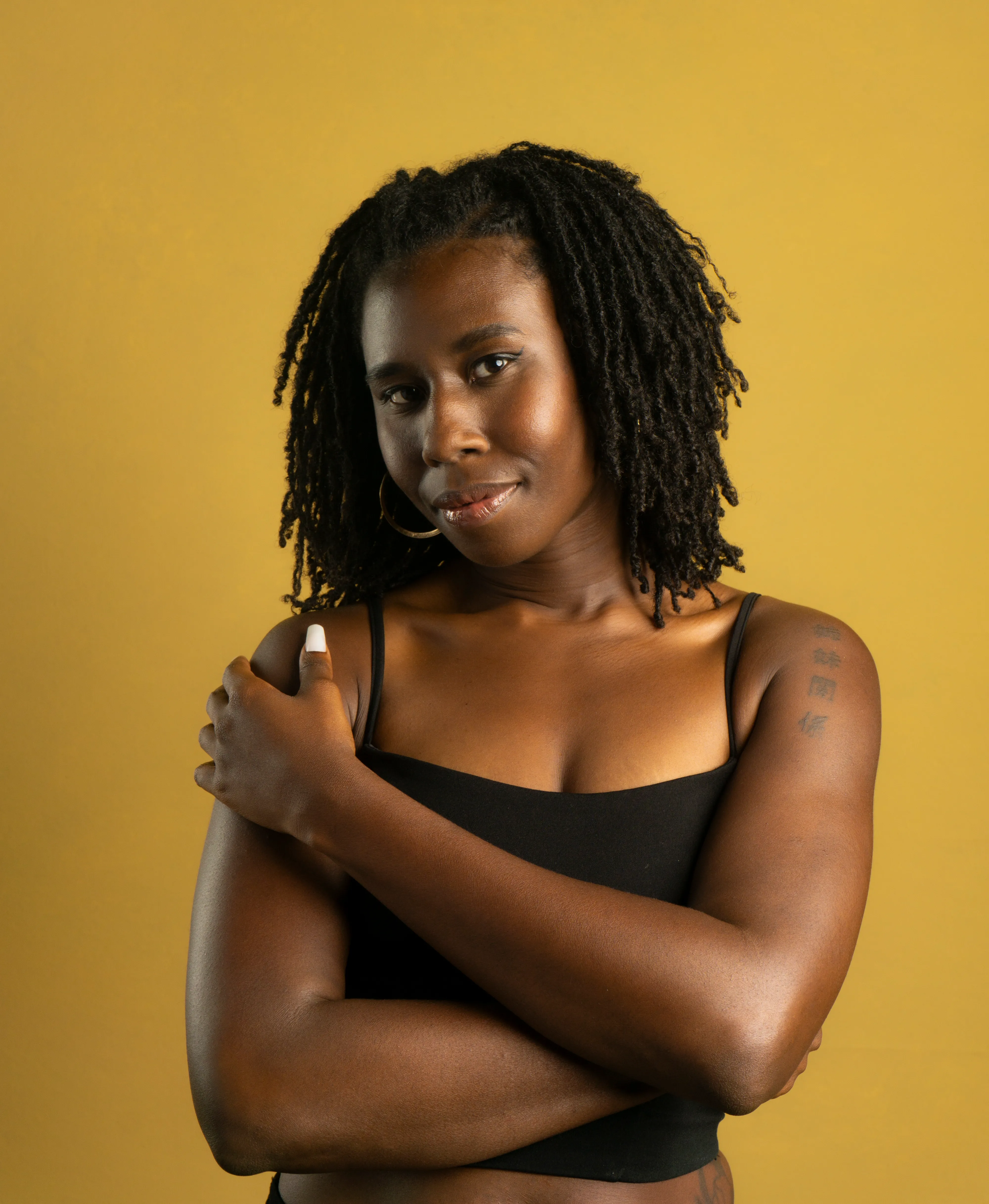 Nala with arms crossed against a yellow studio backdrop